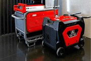Two power generators, one red and one black, on a reflective surface.